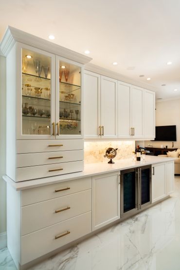 Elegant white kitchen cabinetry with glass doors and gold-handled drawers.