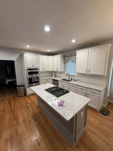 Modern kitchen with white cabinets and marble countertops.