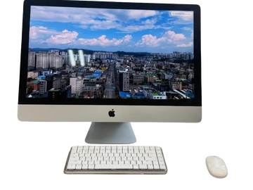 An iMac with a wireless keyboard and mouse showing a cityscape on the screen.