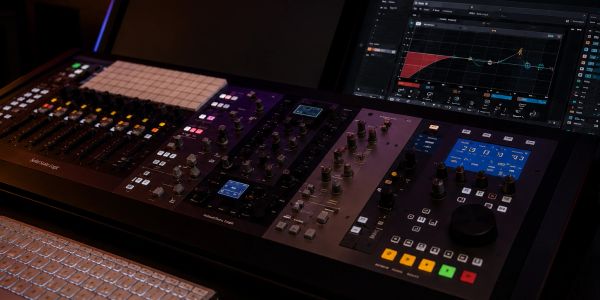 Audio mixing console with multiple knobs, buttons, and displays.