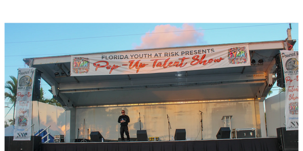 wide view of covered mobile stage with large “Pop-Up Talent Show” banner and side branding