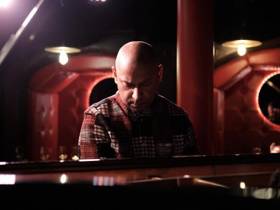 Man playing piano in dimly lit room.