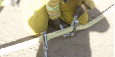 Firefighter using a hose clamp on a firehose
