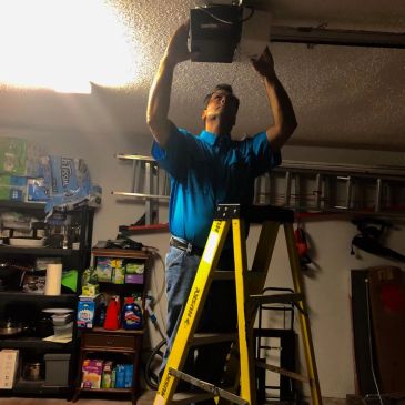 Man fixing garage ceiling fixture on ladder.