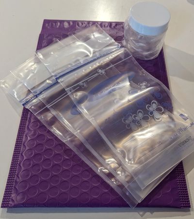 Purple bubble mailer with various clear plastic bags and a small white container.