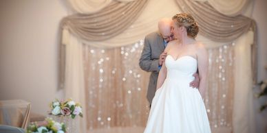 Bride and groom share a tender moment indoors.