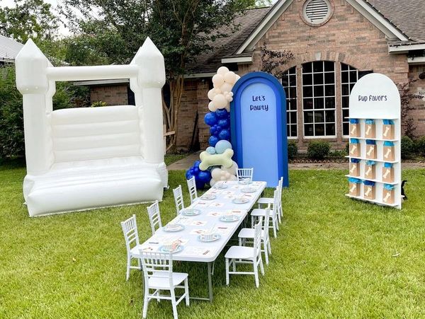 Outdoor dog-themed party setup with bouncy castle and table.