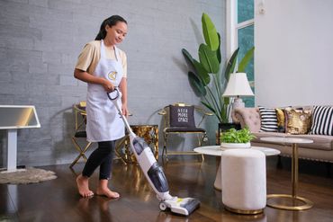 Woman vacuuming a stylish living room with a white vacuum cleaner.