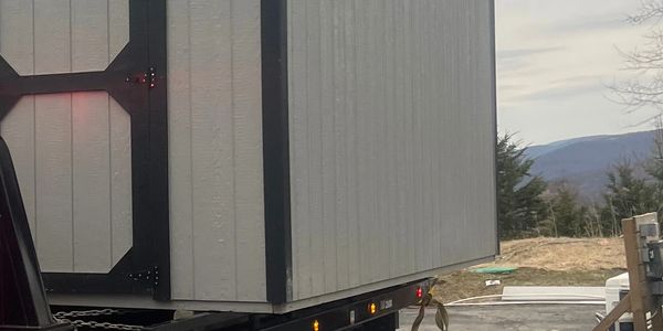 Danny's Towing hauling a shed on a flatbed truck in Kingston, NY. Secure and professional transport.