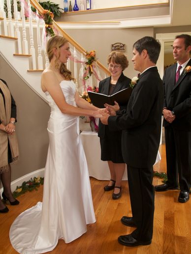 A photograph of a bride and a groom at a wedding, with an officiant.