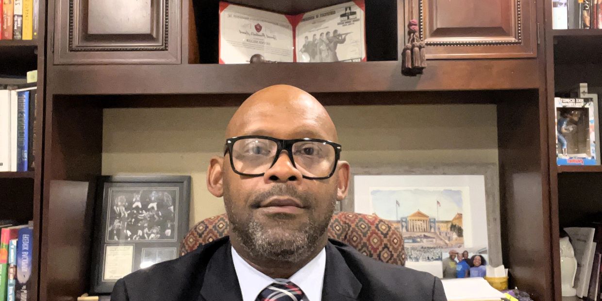 Man wearing glasses and suit sitting in an office.