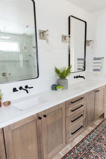 Modern bathroom vanity with double sinks, wooden cabinets, and decorative plants.