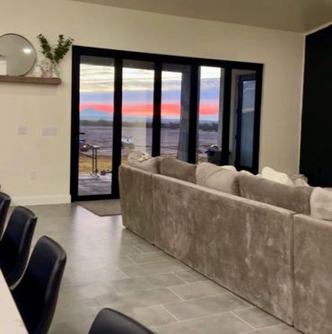 Modern living room with large glass doors showcasing a colorful sunset.
