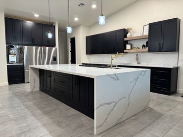 Modern kitchen with black cabinets and white marble island.