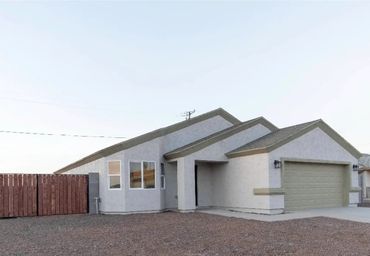 Modern single-story house with a large gravel yard and wooden gates.