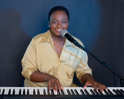 Canangela, piano and voice instructor, singing at a keyboard/piano.