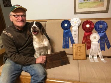 happy man with dog and award ribbons