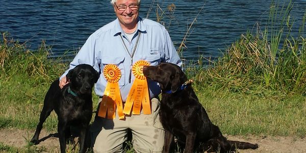 happy man with hunting dogs and award ribbons