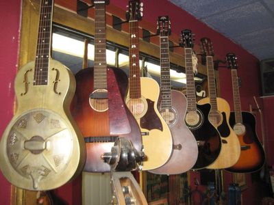 Guitar wall, featuring a variety of traditional and unique acoustic guitars. 