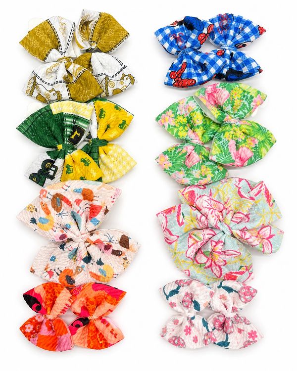Colorful fabric bows with various patterns arranged in two columns.