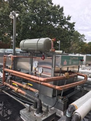 Industrial HVAC unit with copper piping and pressure gauges outdoors.