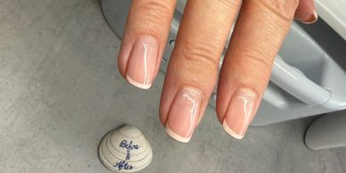Hand with neatly manicured French tip nails above a 'Before & After' shell.