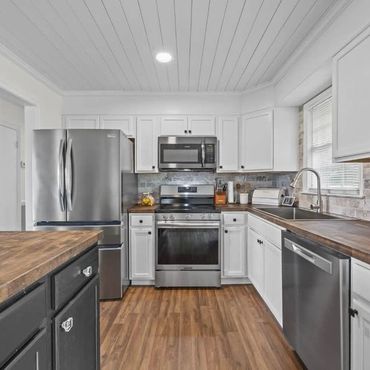 Modern kitchen with white cabinets and stainless steel appliances.