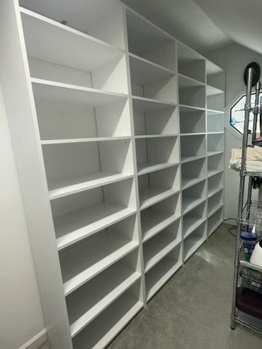Large white empty shelving unit in a room with a small window.