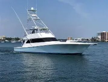A sleek white yacht cruising on calm waters near a coastal city.
