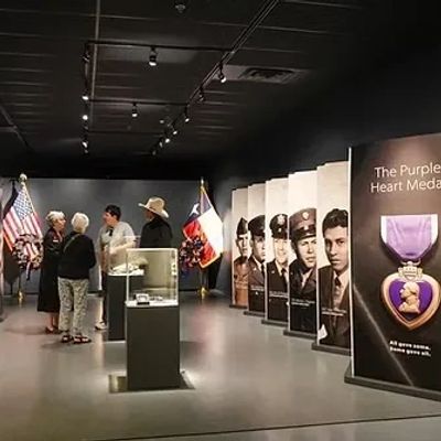 Visitors exploring a Purple Heart Medal exhibit in a museum.