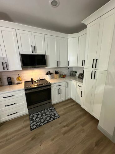 Modern kitchen with white cabinets and black handles.