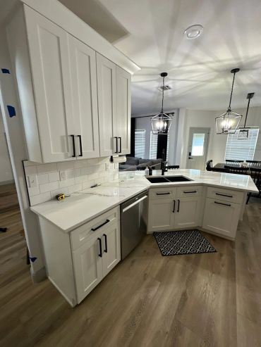 Modern white kitchen with stainless steel sink and appliances.