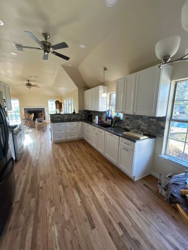 Spacious kitchen with white cabinets and wood flooring.