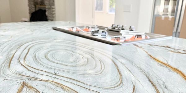 Close-up of a modern kitchen island with a natural stone countertop and built-in stove.
