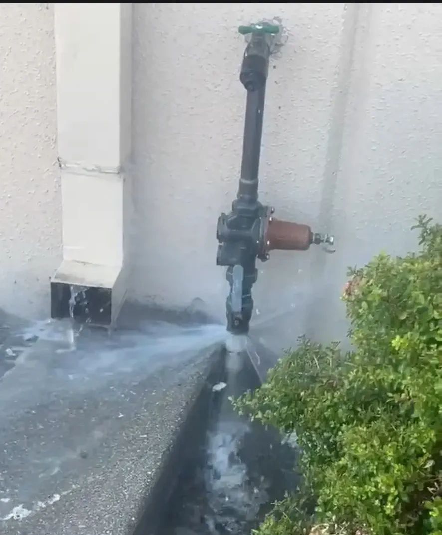 Leaking outdoor water pipe spraying water at a commercial building in Morgan Hill, CA