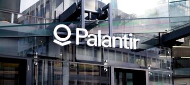 Palantir company logo on a modern glass building facade.
