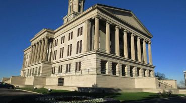 Historic government building with tall columns under a clear blue sky.