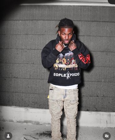 Man posing in stylish hoodie and star-patterned pants.