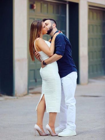 Couple kissing in at their engagement shoot in Toronto. Bride to be is wearing a white dress.