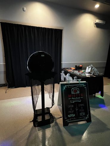 A spooky photo booth setup with props and skeleton decorations.