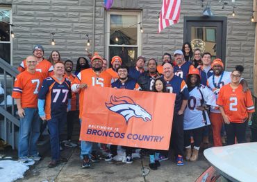 Group of Denver Broncos fans holding a banner that says "Baltimore is Broncos Country."