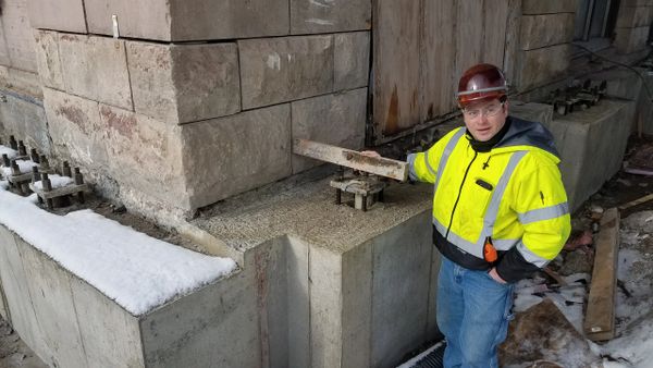 Construction worker inspecting a stone foundation during winter.