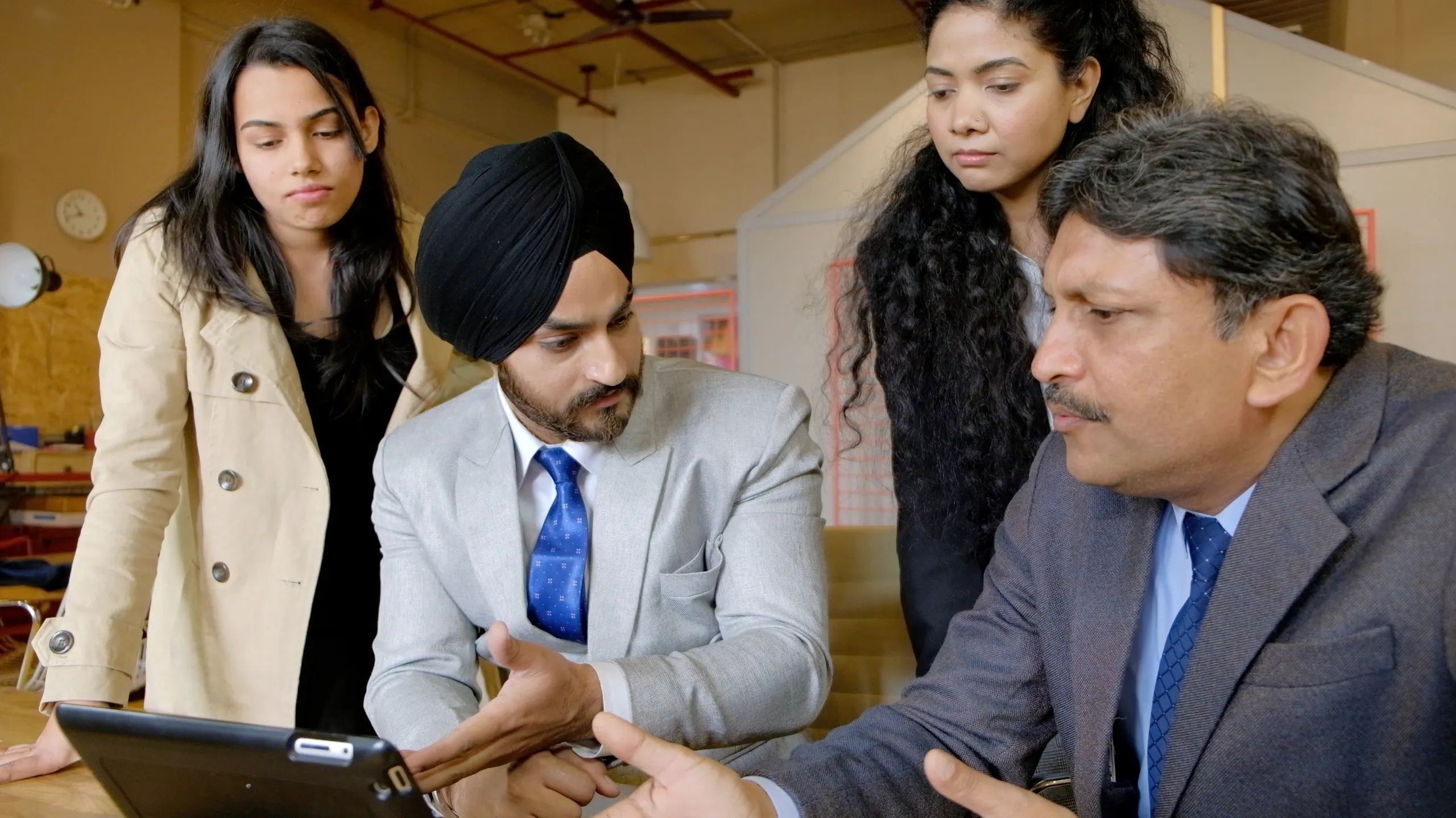 A group of professionals discussing something on a tablet in an office.
