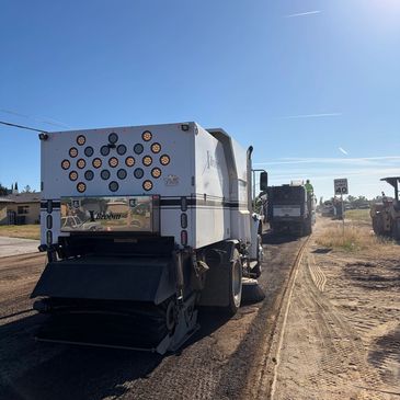 A large white semi-truck with multiple rear lights parked on a dirt road under a clear blue sky.
