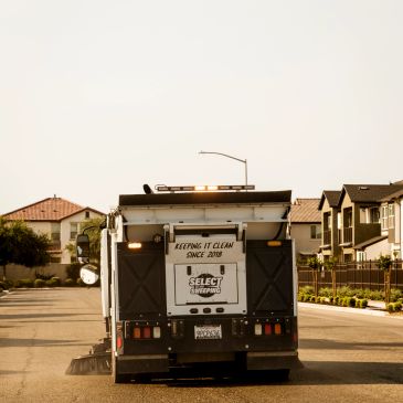 Street sweeper truck cleaning a residential neighborhood.