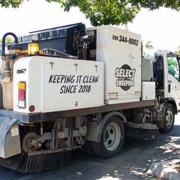 Street sweeping truck parked under a tree, promoting cleanliness since 2018.