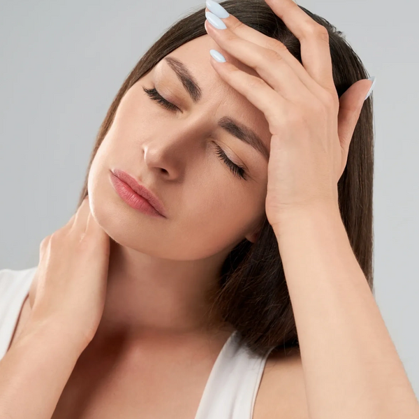 Woman with closed eyes holding her forehead and neck, appearing to have a headache.