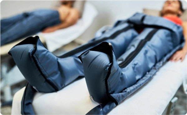 Person undergoing leg compression therapy with specialized inflatable boots.