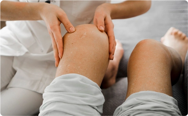 Therapist performing knee massage on a patient.