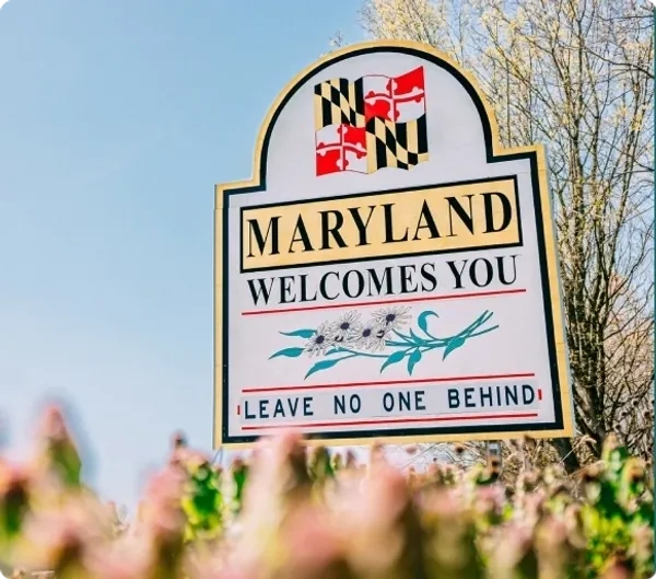 Maryland welcome sign with state flag and floral design.